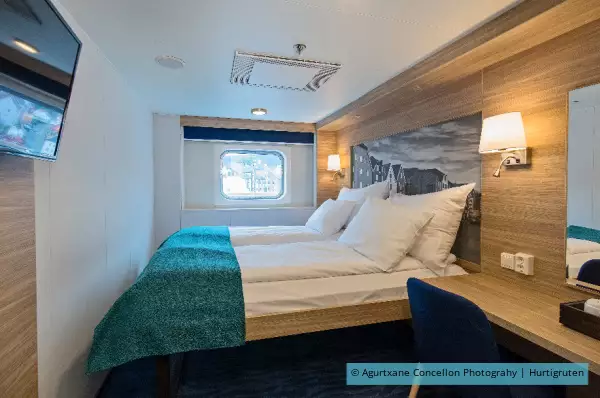 Ein Doppelbett vor dem Fenster.