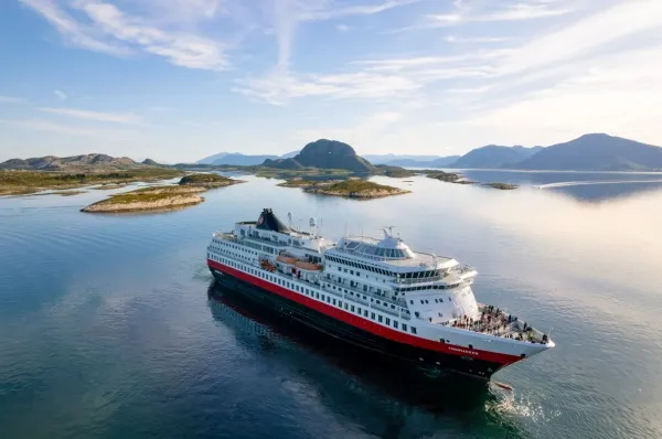 Die MS Finnmarken fährt entlang der sonnenbeschienenen Küste von Helgoland.