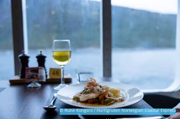 Meeresfrüchte Teller und Weinglas im Restaurant auf dem Schiff mit Ausblick auf einen norwegischen Fjord.
