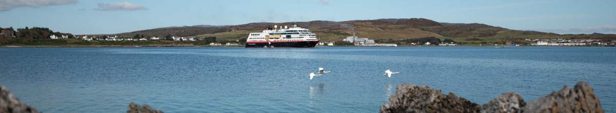 Ein Kreuzfahrtschiff fährt vor der schottischen Insel Islay.