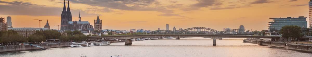 Die Stadt Köln bei Sonnenuntergang. Zu sehen ist der Dom und die Hohenzollernbrücke.
