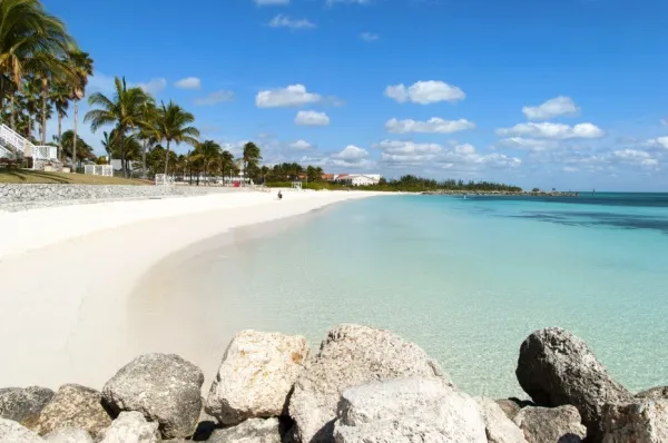 Der weite, weiße Strand von Freeport auf den Bahamas mit Steinen und Palmen.