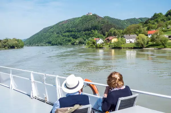 Zwei Menschen sitzen auf dem Sonnendeck eines Kreuzfahrtschiffes.