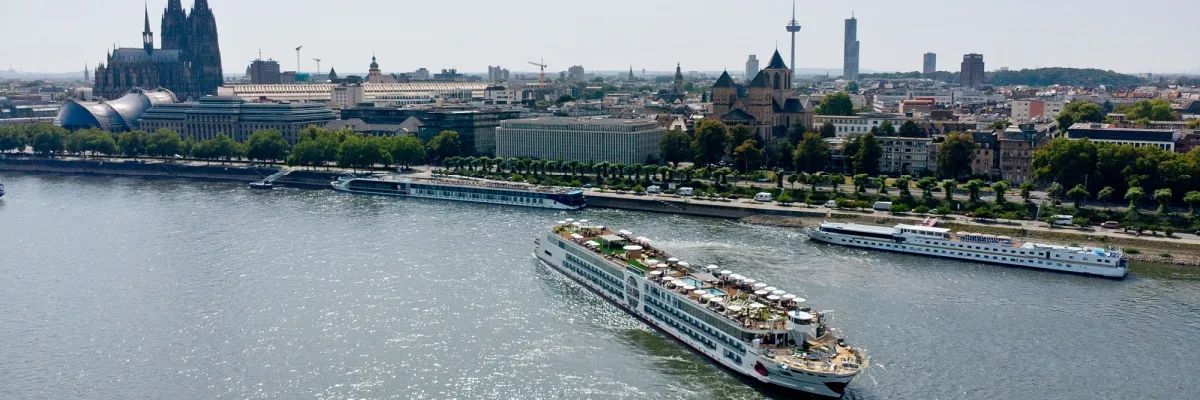 Das Flussschiff A-ROSA Sena auf dem Rhein vor der Anlegestelle in Köln. Im Hintergrund sind links der Kölner Dom und der Musical Dome, sowie rechts die Basilika St. Kunibert und der Colonius-Turm zu sehen.