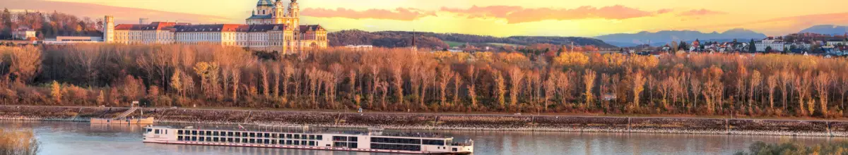 Ein Kreuzfahrtschiff fährt während des Sonnenuntergangs über die Donau.