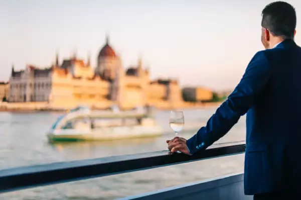 Ein Mann blickt von einem Schiffsgeländer auf das Parlament in Budapest.