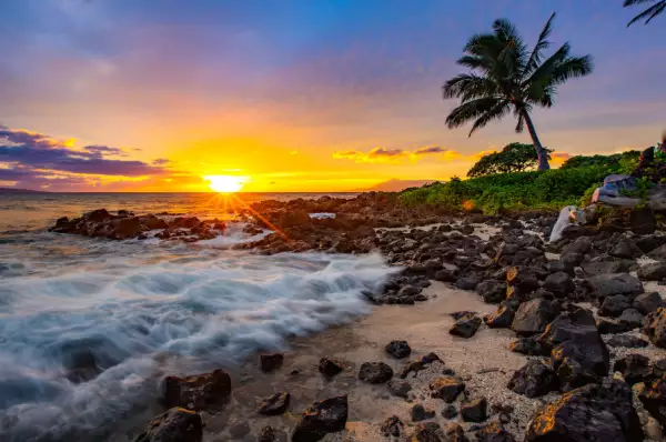 Strand auf Maui, im Hintergrund geht die Sonne unter.