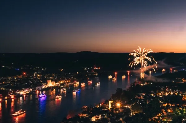 Rhein in Flammen Flusskreuzfahrt Ein Feuerwerk am Rhein, viele kleine Boote sind unterwegs und die Sonne geht im Hintergrund unter.
