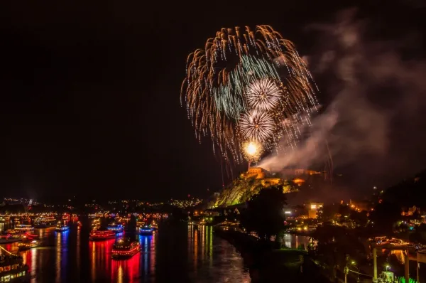 Rhein in Flammen Flusskreuzfahrt Ein Feuerwerk am Rhein auf einem Berg bei Nacht. Kleine Boot und Flusskreuzfahrtschiffe liegen im Wasser.