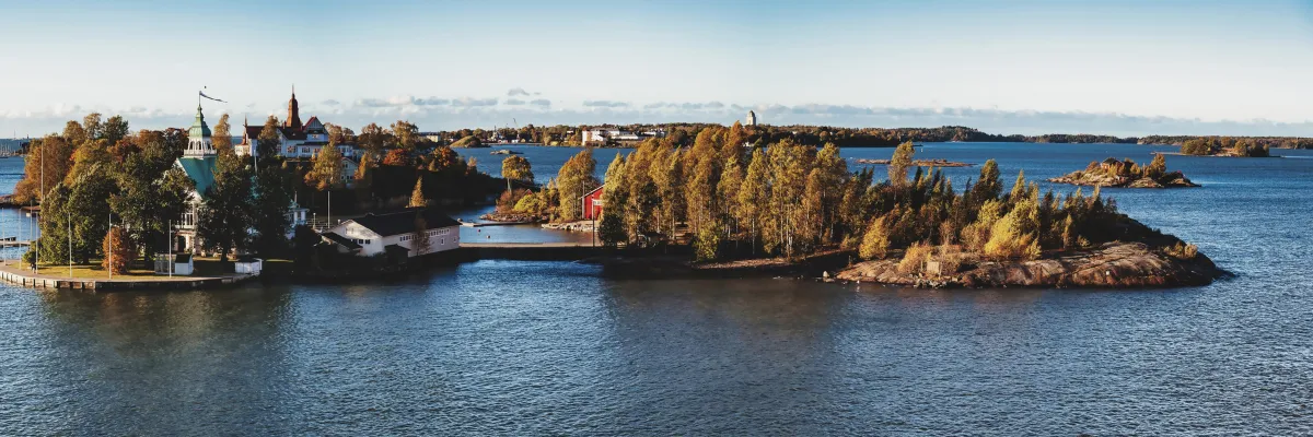 Panoramaansicht der schwedischen Schärenlandschaft mit kleinen Inseln, herbstlich gefärbten Bäumen, historischen Gebäuden und ruhiger Ostsee.