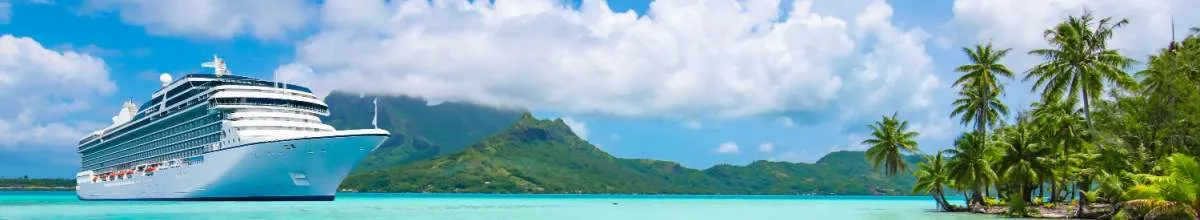Banner-Bild für die Gründe einer Karibik-Kreuzfahrt: Ein großes Kreuzfahrtschiff ankert in einer Bucht mit leuchtend türkisfarbenem Wasser vor der Kulisse von üppig grünen, tropischen Bergen und Palmen.