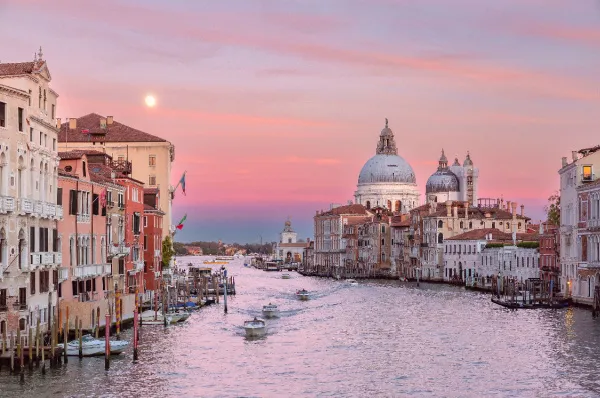 Blick auf den Canal Grande in Venedig mit Gondeln und historischen Palästen bei Sonnenuntergang, Symbol für die kulturellen Schätze einer Mittelmeerkreuzfahrt.