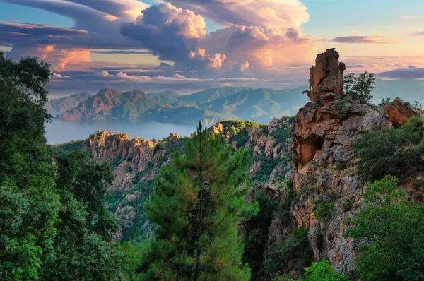 Spektakuläre rote Felsformationen an einer Steilküste mit türkisblauem Wasser im Mittelmeer, Symbol für die atemberaubenden Landschaften einer Kreuzfahrt.