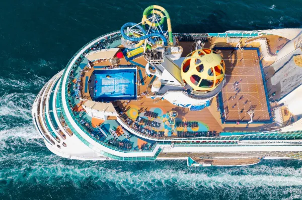Großes, modernes Kreuzfahrtschiff mit zahlreichen Decks und sichtbaren Freizeiteinrichtungen, Symbol für den Komfort und die Bequemlichkeit eines schwimmenden Hotels auf einer Mittelmeerkreuzfahrt.