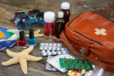 Reiseapotheke mit Medikamenten, Pflastern und Reiseutensilien als Vorbereitung gegen Seekrankheit auf einer Kreuzfahrt.