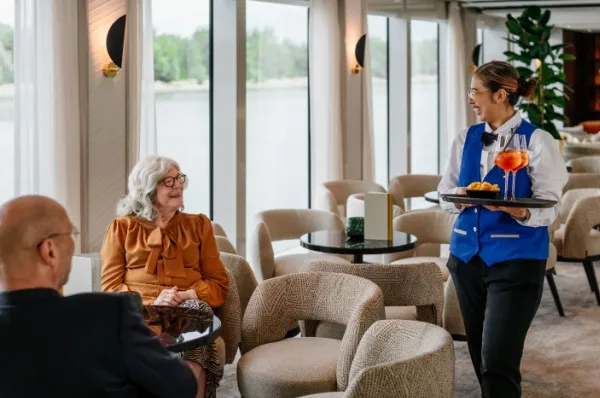 Flusskreuzfahrt mit AMADEUS Eine Kellnerin bringt Gästen auf einem Flusskreuzfahrtsschiff Getränke.