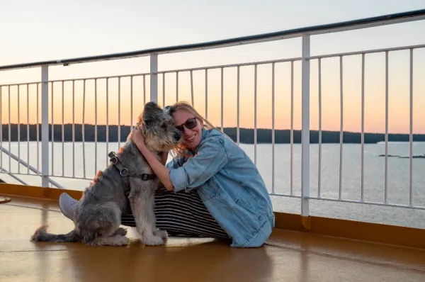 Eine Freu umarmt ihren zotteligen Hund auf einem Kreuzfahrtschiff.