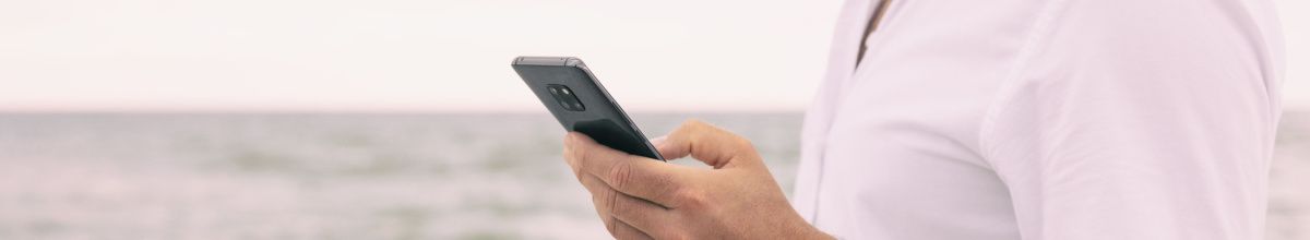 Mann hält Smartphone in der Hand an Bord eines Kreuzfahrtschiffes.