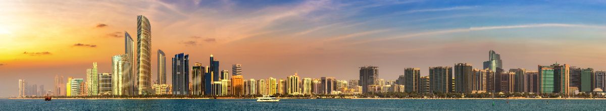 Panorama einer modernen orientalischen Skyline mit Wolkenkratzern am Meer bei Sonnenuntergang, Symbol für eine Orient Kreuzfahrt zu den besten Reisezeiten.