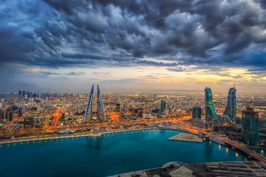Moderne Skyline einer orientalischen Metropole bei Nacht mit beleuchteten Wolkenkratzern und dramatischem Himmel, Symbol für eine Orient Kreuzfahrt.