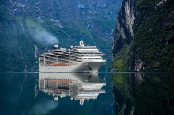 Ein Kreuzfahrtschiff liegt umgeben von Bergketten im Wasser.