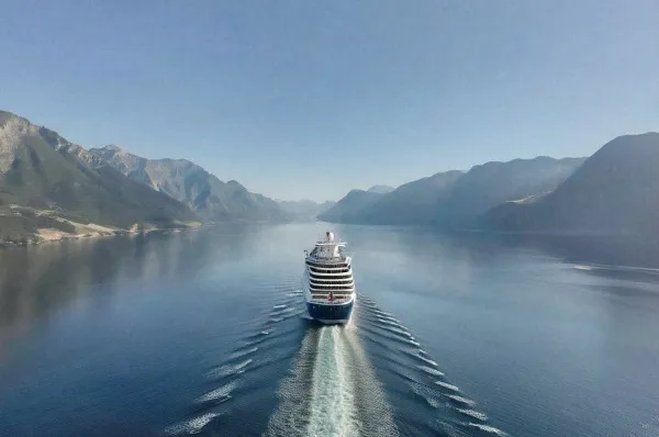 Ein Kreuzfahrtschiff fährt zwischen zwei Bergketten hindurch.