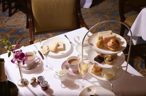 Frühstück an Bord von Cunard Line. Zwei Tassen Kaffe und ein Korb mit Gebäck stehen auf einem Tisch.