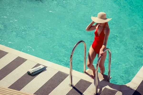 Eine Frau steigt aus einem Pool der Cunard Line: Sie hat Ihre Kreuzfahrt im Premium Preismodell gebucht und reist mit dem attraktivsten Tarif.