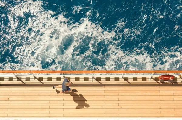 Ein Mann joggt an Deck mit Aussicht auf das Meer: Er hat seine Kreuzfahrt bei Cunard kurzfristig gebucht und reist jetzt mit dem Sparpreis für spontane Reisende.