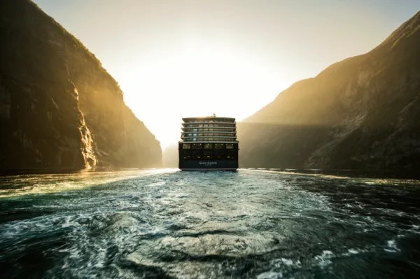 Das Luxus-Kreuzfahrtschiff "Queen Elizabeth" fährt bei Sonnenuntergang durch die norwegischen Fjorde.