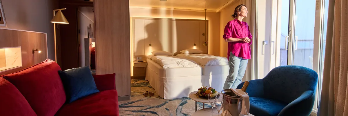 AIDA Evolution: Neues Kabinen- und Suiten-Design an Bord Modernisierte Suite an Bord im Rahmen von AIDA Evolution mit eleganter Einrichtung, Sitzecke und privatem Balkon.