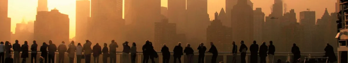 Eine Reihe Kreuzfahrtpassagiere fährt bei Sonnenuntergang in den Hafen von New York City ein und bestaunt die Skyline.