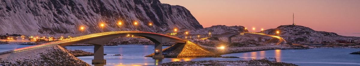 Eine Flussbrücke in Molde bei Sonnenuntergang mit warmer Beleuchtung und einem Berg im Hintergrund.