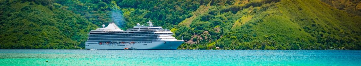 Kreuzfahrtschiff in Südostasien. Das Schiff fährt auf dem türkis-blauen Meer und grüne Berge befinden sich im Hintergrund.