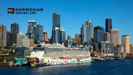 Norwegian Encore Norwegian Encore Seitenansicht mit buntem Bug-Design am Hafen von Seattle direkt vor der Skyline.