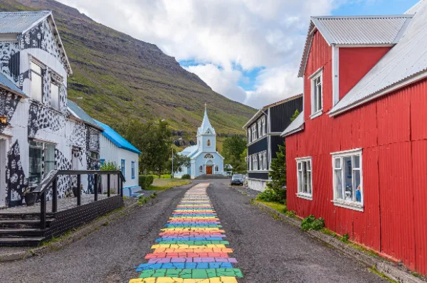 Das Skatfell Kulturzentrum und die bunten Straßen der Stadt bei Sonnenschein mit einem Berg im Hintergrund.
