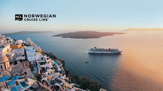 Norwegian Jade Seitenansicht der Norwegian Jade mit jadegrünem Bug-Design vor der Küste von Santorini in Griechenland im Sonnenuntergang.