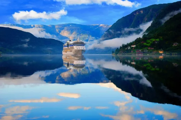 Ein großes Kreuzfahrtschiff fährt durch die klaren Gewässer eines norwegischen Fjords.