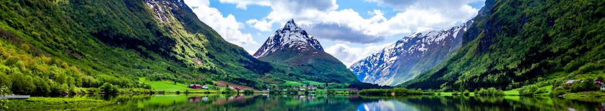 Ein malerischer Fjord in Nordeuropa mit hohen Bergen, auf deren Gipfeln Schnee liegt.