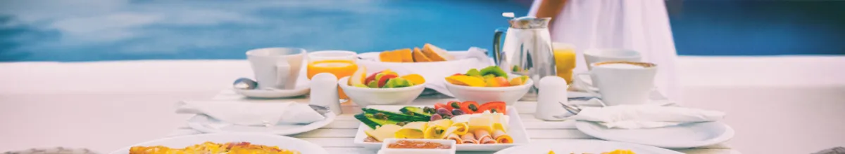 Ein reiches Frühstück an Bord eines Schiffes mit dem Meer im Hintergrund.