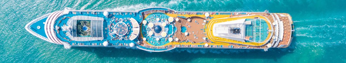 Luftaufnahme eines Kreuzfahrtschiffes im Meer, zeigt die bunten Pool- und Sonnendecks aus der Vogelperspektive. Bild passend zum Thema Stornokabinen und günstige Kreuzfahrten.