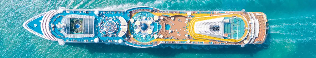 Luftaufnahme eines Kreuzfahrtschiffes im Meer, zeigt die bunten Pool- und Sonnendecks aus der Vogelperspektive. Bild passend zum Thema Stornokabinen und günstige Kreuzfahrten.