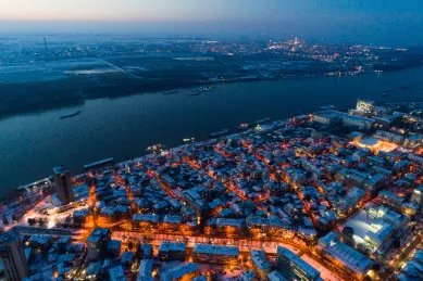 Eine Luftaufnahme der bulgarischen Stadt Rousse bei Nacht mit warm beleuchteten Gassen und Fenstern.