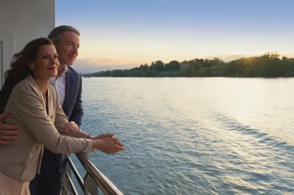 Paar genießt den Sonnenuntergang vom Balkon einer AMADEUS Flusskreuzfahrt auf dem Rhein