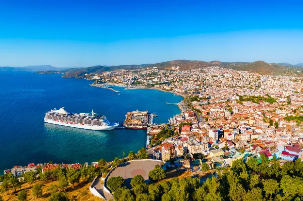 Großes Kreuzfahrtschiff im Hafen einer sonnigen Küstenstadt, Symbol für eine erlebnisreiche Sommerferien-Kreuzfahrt für die ganze Familie.