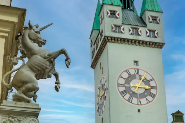 Rechts eine Statue von einem Pferd, links ein grüner Glockenturm.