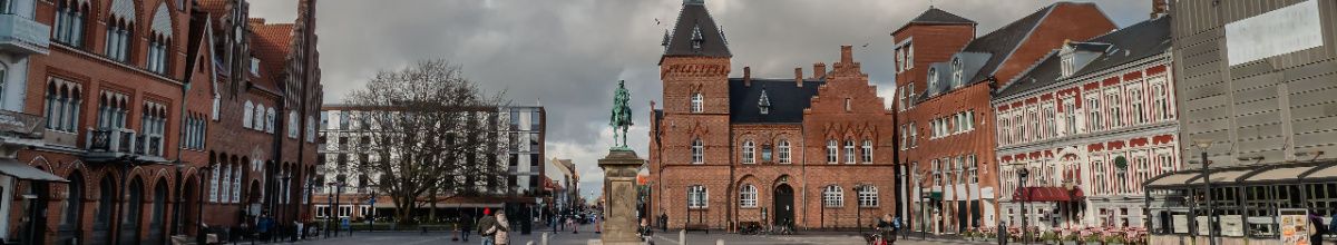 Der Marktplatz von Esbjerg mit einer Reiterstatue, Passanten und Gebäuden.