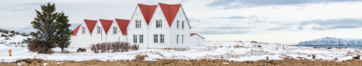 Ein Bauernhof im Winter bei Hafnarfjörður mit verschneiter Landschaft im Hintergrund bei Tag.