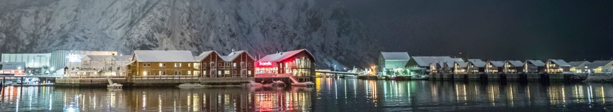 Die Gebäude der Stadt inmitten eines stillen Winters bei Nacht am Wasser des Fjords.