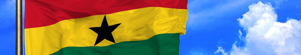 Die Flagge von Ghana wie sie im Wind weht mit einem blauen Himmel im Hintergrund.